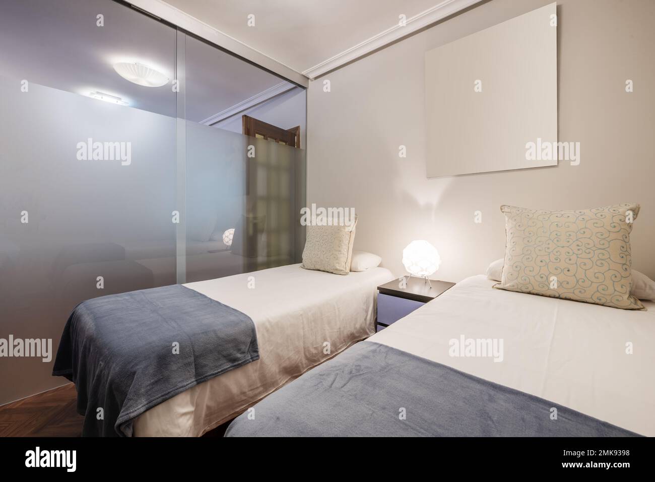 Bedroom with two single beds with white bedspreads, blue blankets and a