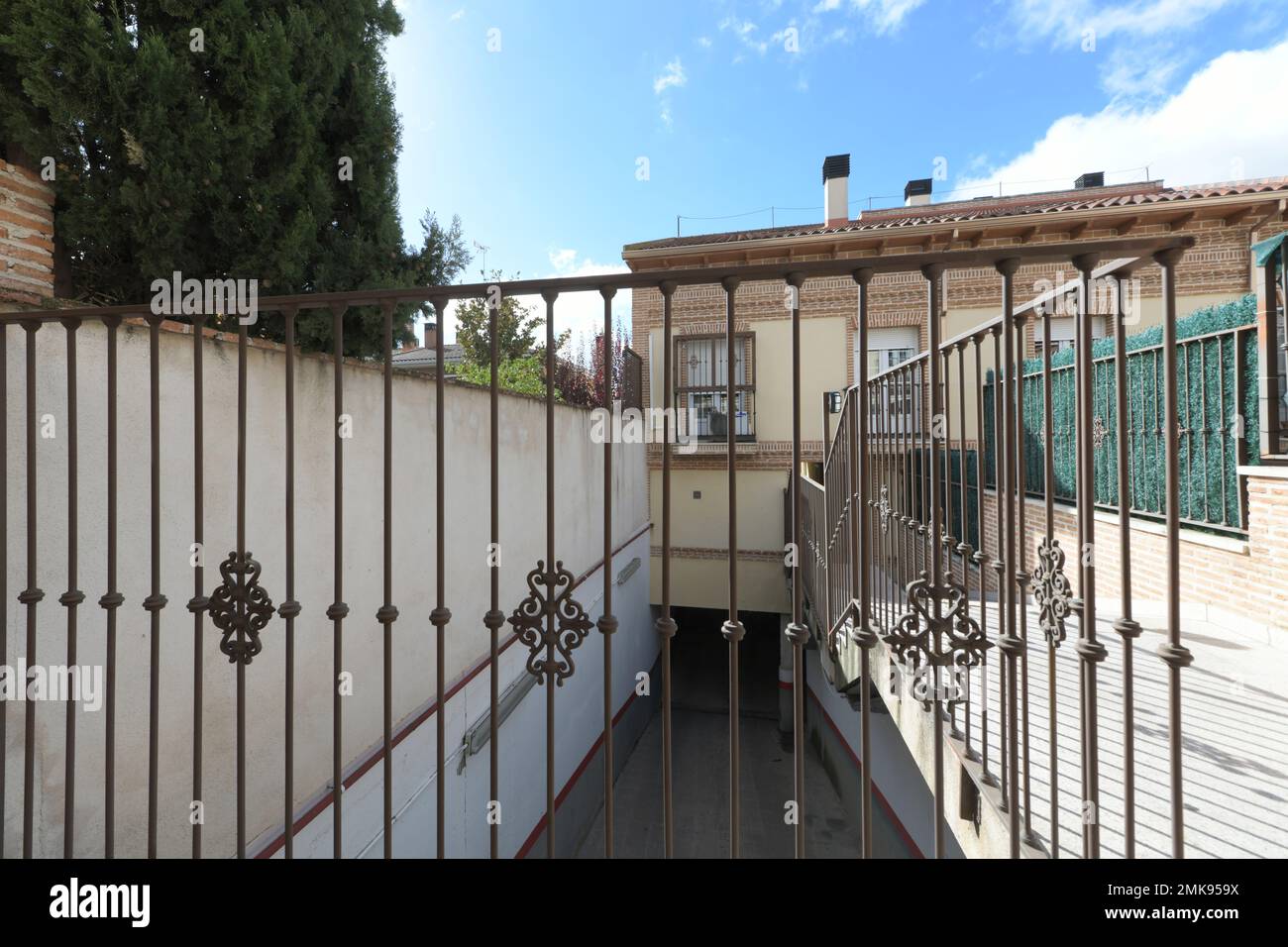 wrought iron railing of a walkway next to a ramp down to a garage Stock ...