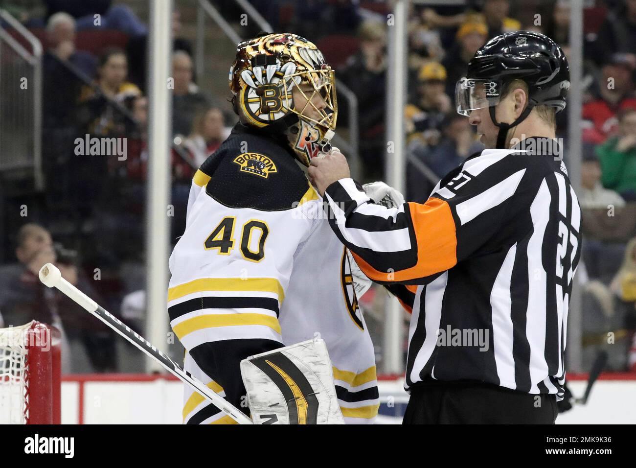 Referee Eric Furlatt (27) adjusts the mask of Boston Bruins goaltender Tuukka  Rask, of Finland, during the second period of the team's NHL hockey game  against the New Jersey Devils, Thursday, March