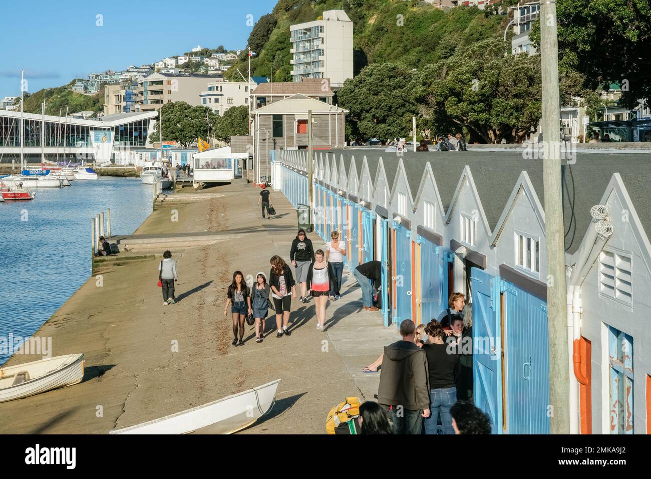 Wellington New Zealand - October 3 2010; People wandering along walkway in front Oriental Bay boat sheds and waterfront. Stock Photo