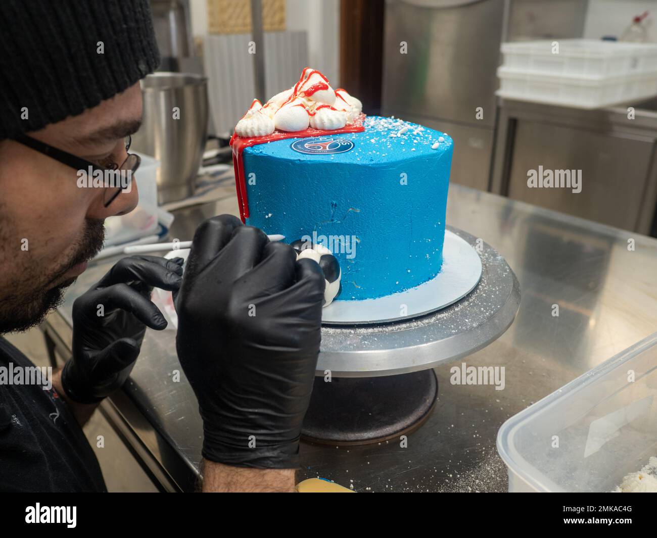 blue sprayed frosted cake on stand dripped with red ganache filling and