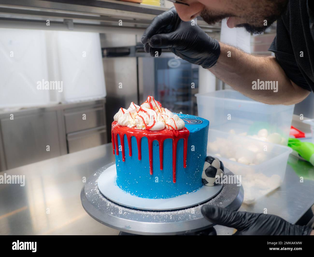 blue sprayed frosted cake on stand dripped with red ganache filling and