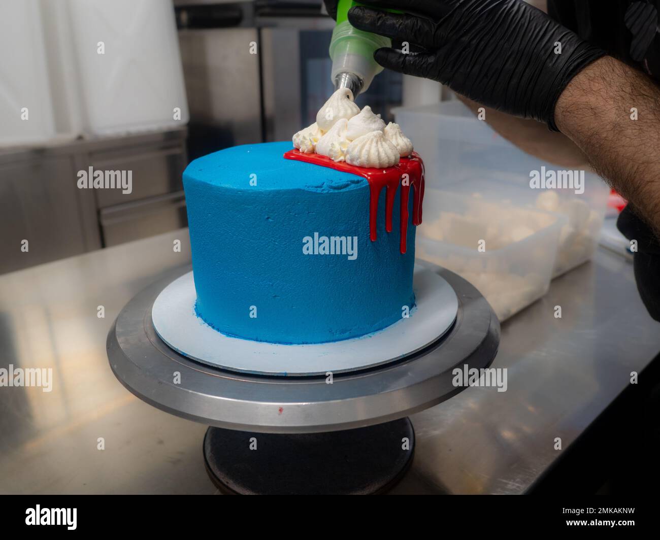 blue sprayed frosted cake on stand dripped with red ganache filling and
