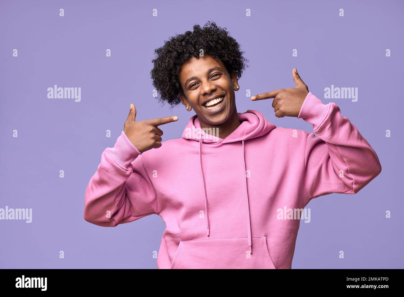 Happy African teen pointing fingers at dental white teeth advertising whitening. Stock Photo