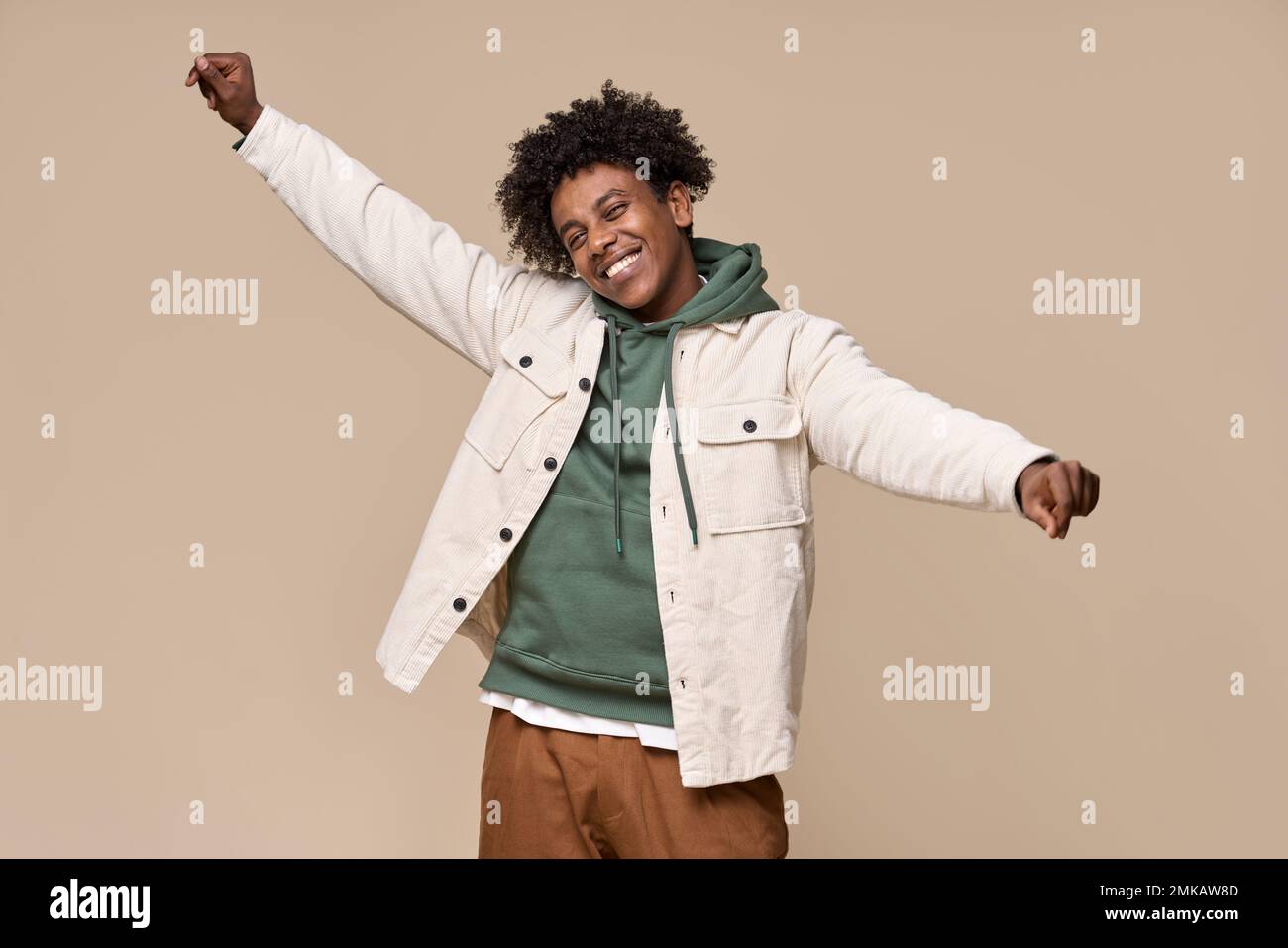 Funky happy African gen z teenager dancing isolated on beige background. Stock Photo