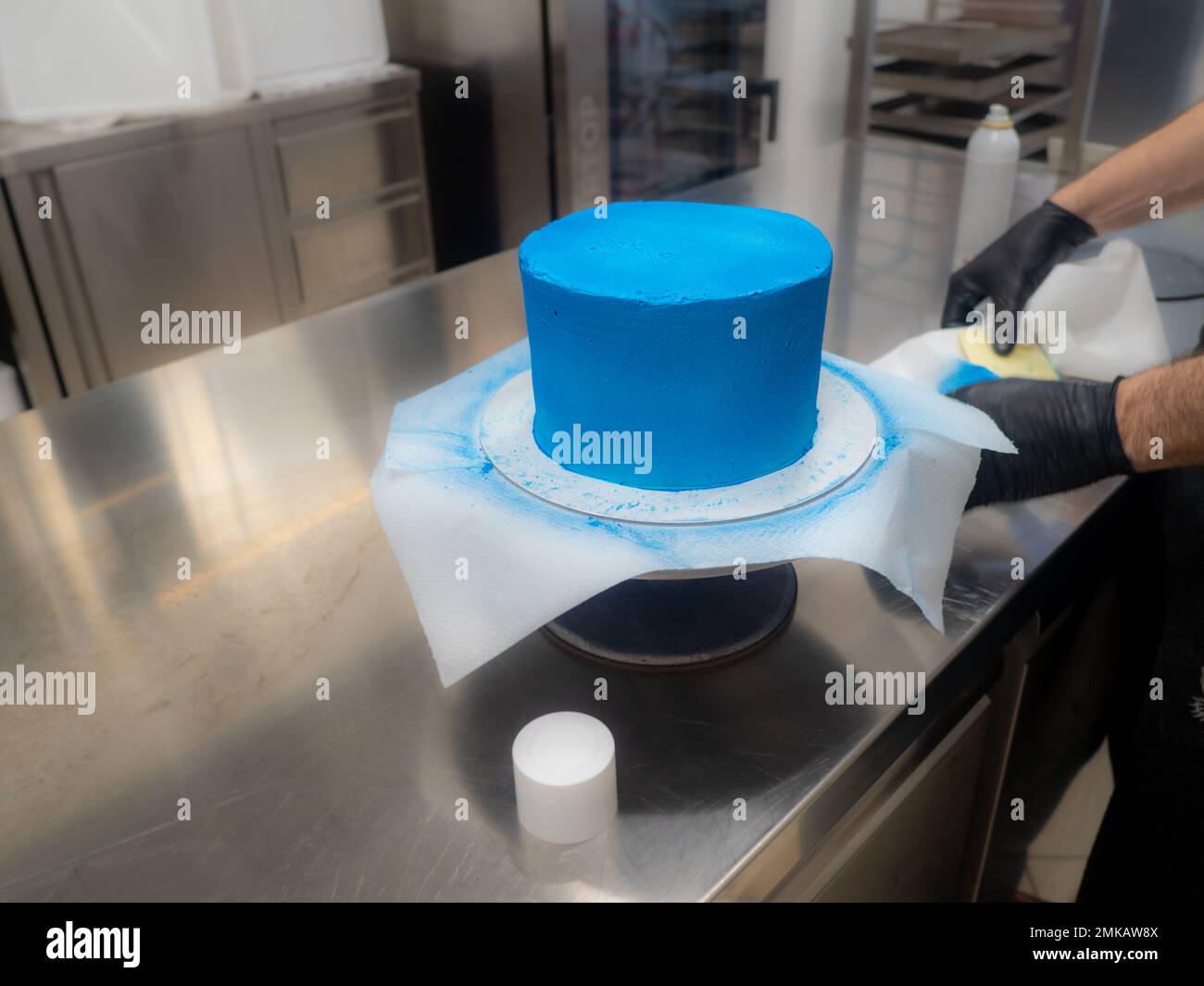 blue sprayed frosted cake on stand ready for decoration at bakery lab