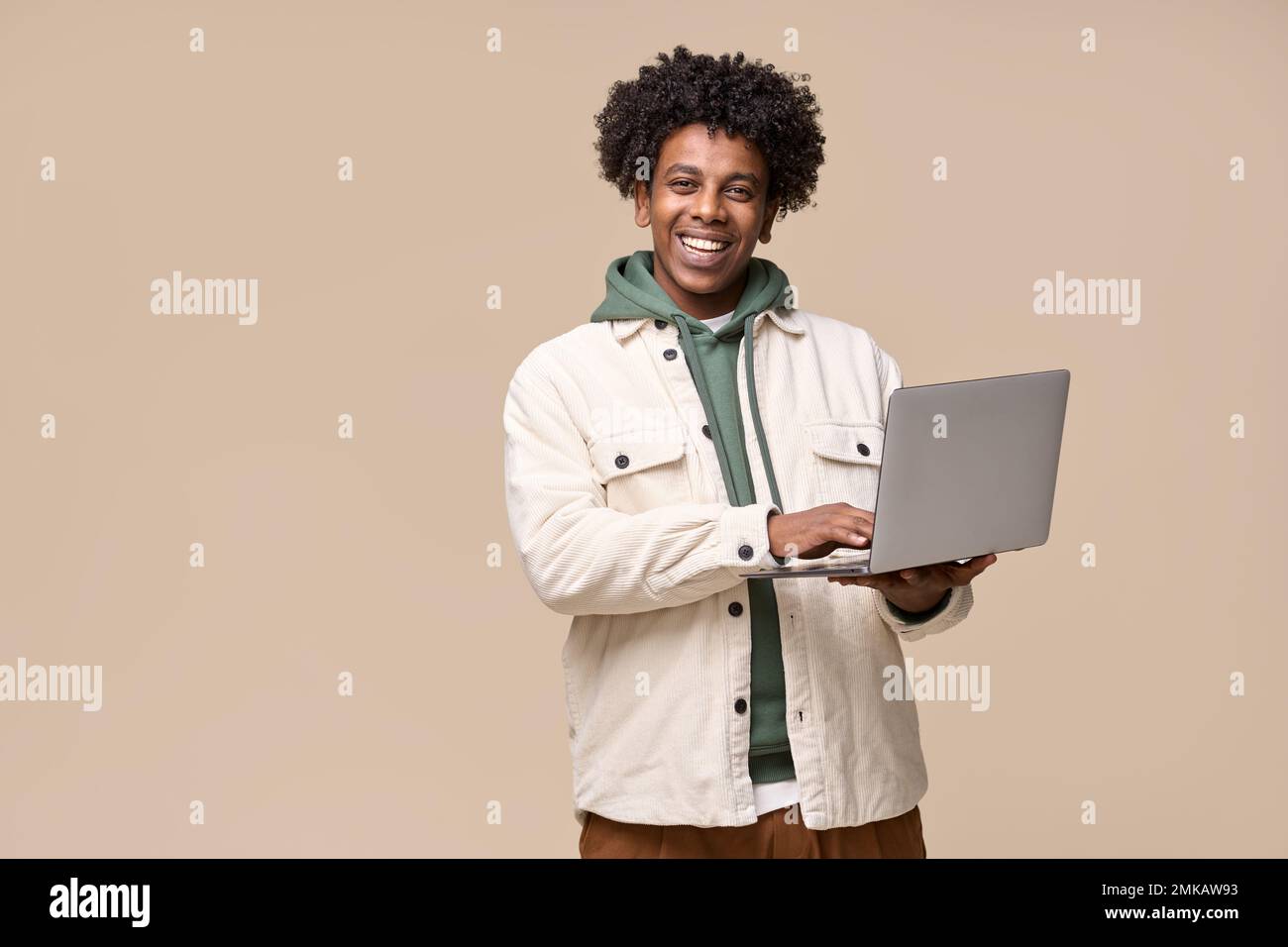 Happy African student holding using laptop isolated on beige background. Stock Photo