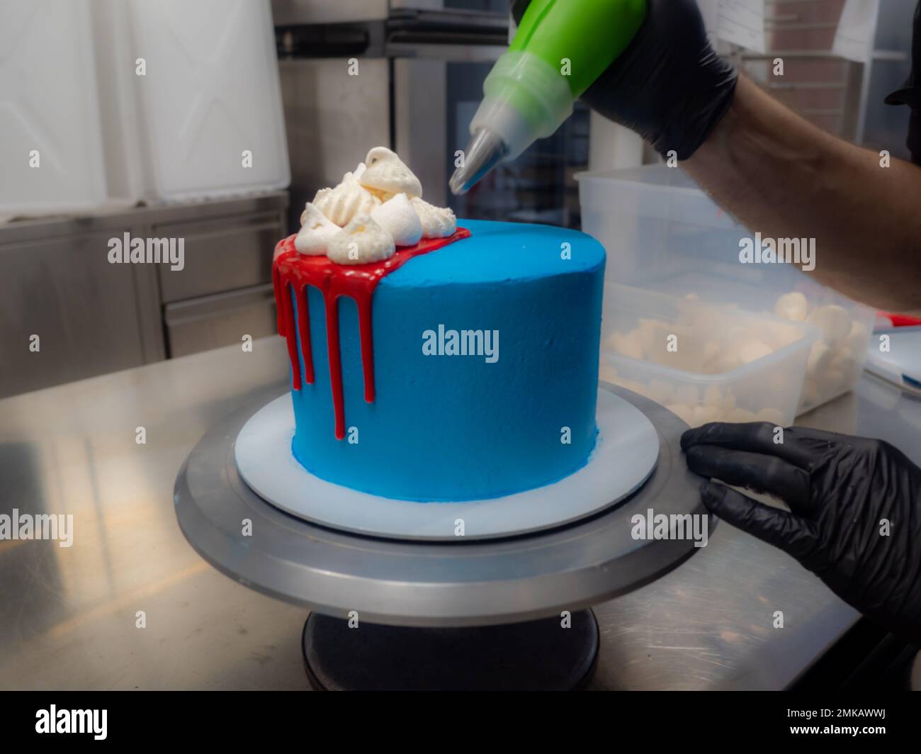 blue sprayed frosted cake on stand dripped with red ganache filling and