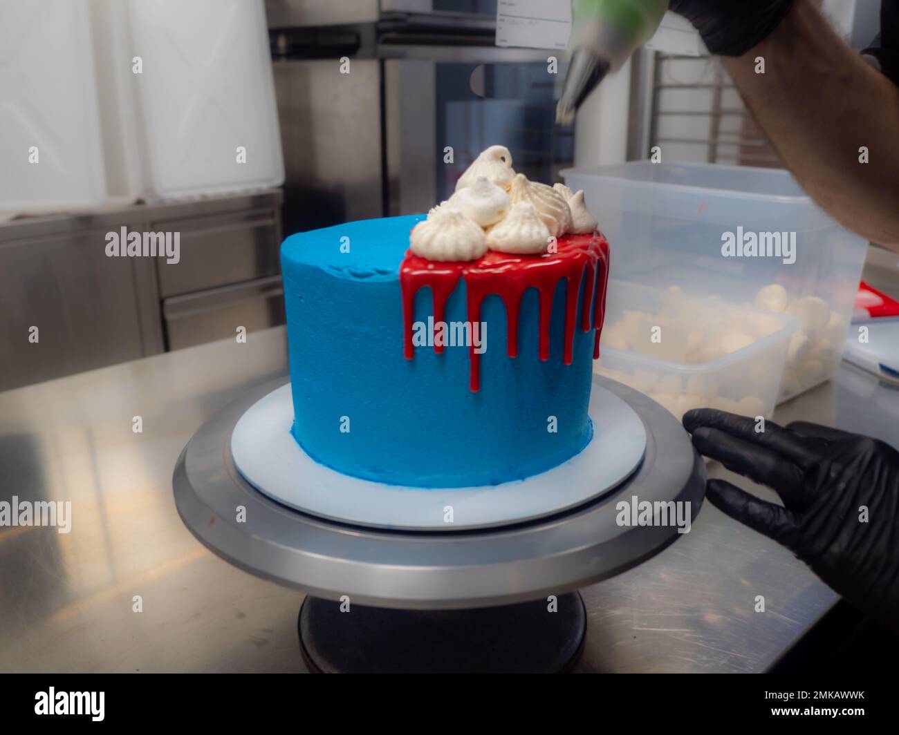 blue sprayed frosted cake on stand dripped with red ganache filling and