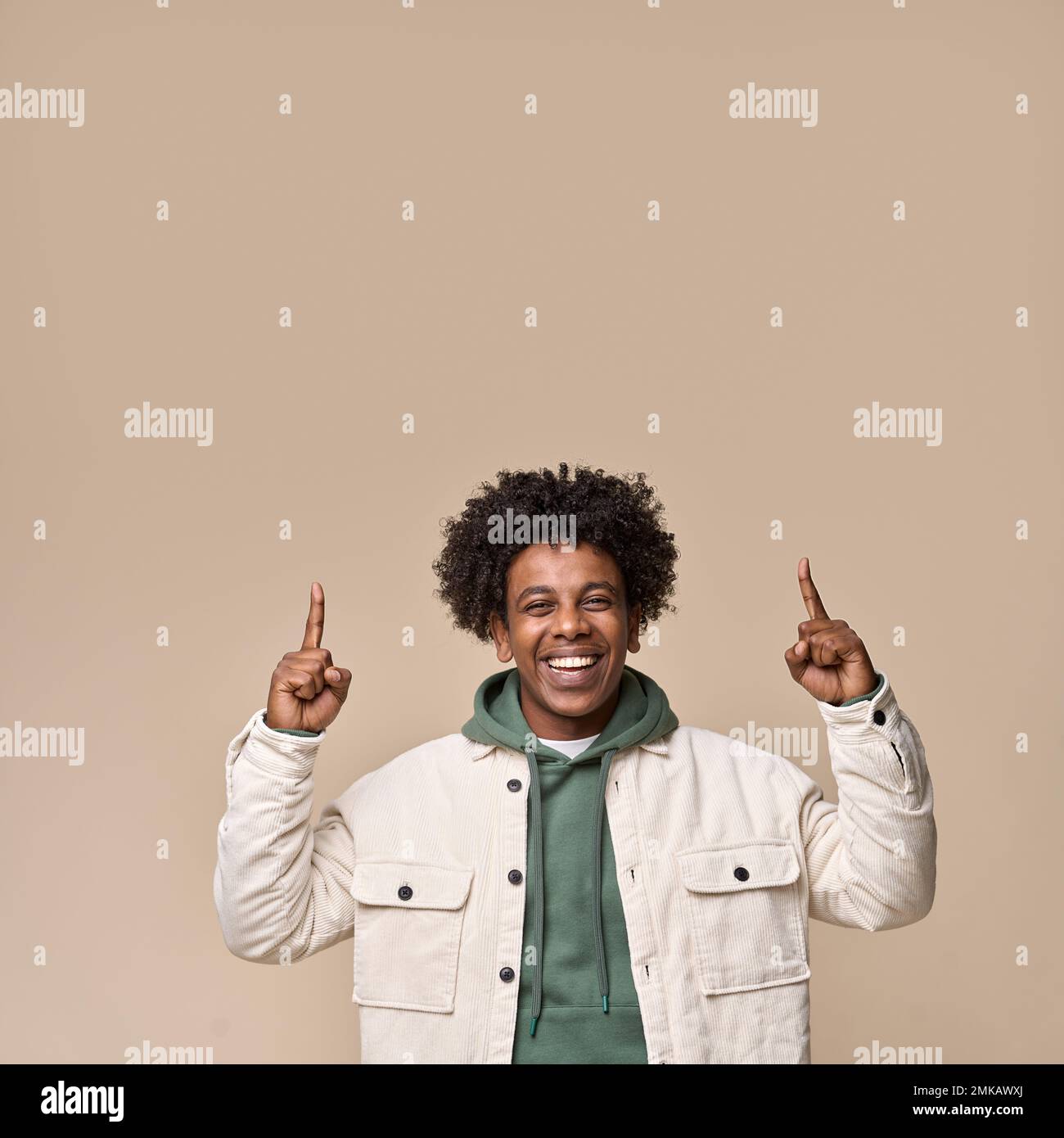 Smiling African teenager pointing fingers up isolated on beige background. Stock Photo