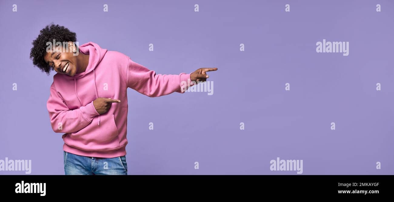 Happy African teen guy pointing fingers aside advertising presenting promotion. Stock Photo