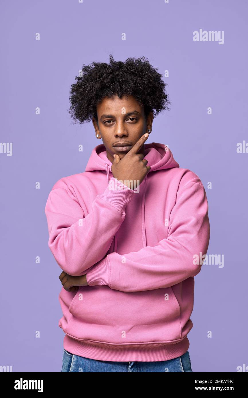 Cool African teen guy wearing pink hoodie isolated on light purple. Vertical Stock Photo