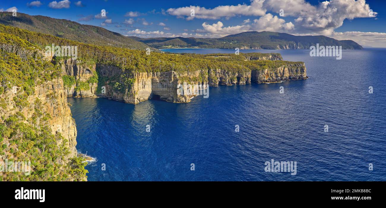 Coastal view of steep sheer cliffs and calm blue ocean at Waterfall Bay