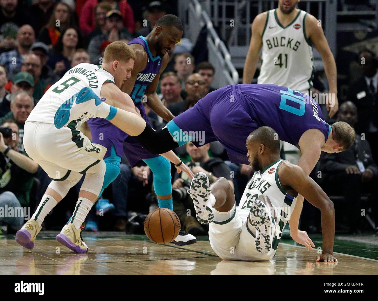Milwaukee Bucks' Donte DiVincenzo (9) and Khris Middleton (22) fight for a  loose ball against Charlotte Hornets' Kemba Walker (15) and Cody Zeller  (40) during the first half of an NBA basketball