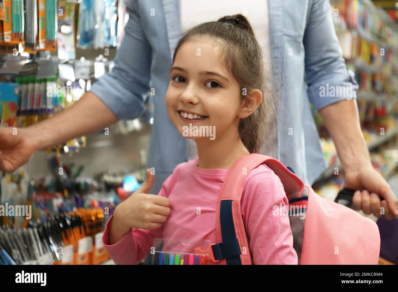 Little girl with father choosing school stationery in supermarket Stock
