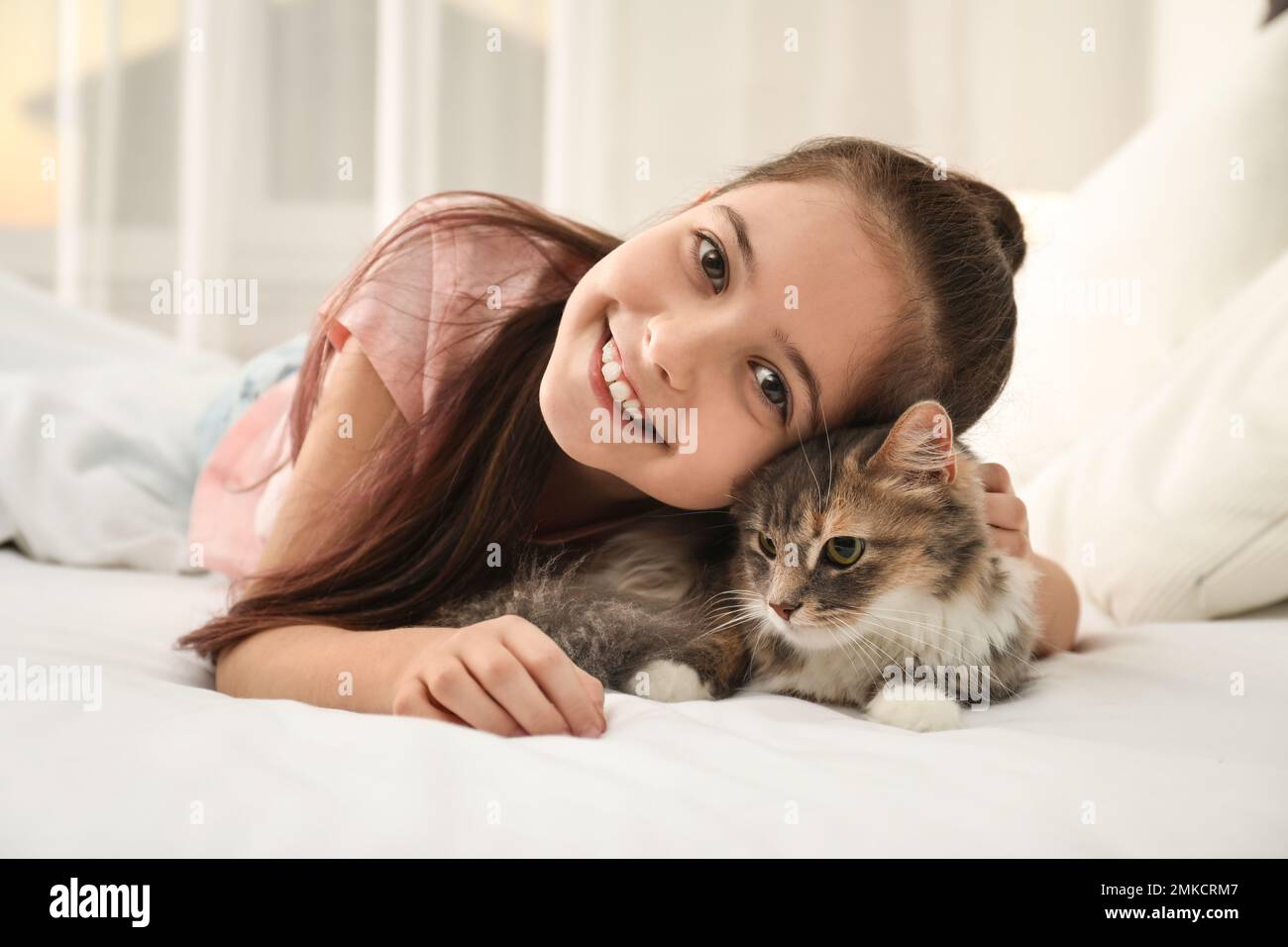 Cute little girl with cat lying on bed at home. First pet Stock Photo ...