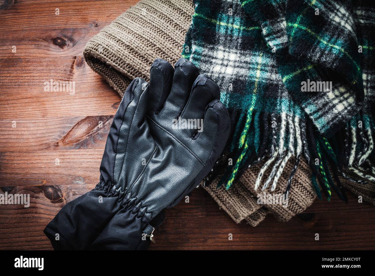 Warm scarves, wool sweaters and colorful winter gloves on wood Stock Photo