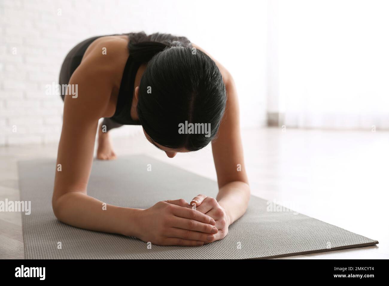 Young woman practicing forearm plank asana in yoga studio. Phalankasana pose variation Stock Photo