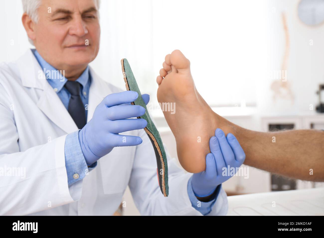 Male orthopedist fitting insole on patient's foot in clinic Stock Photo ...