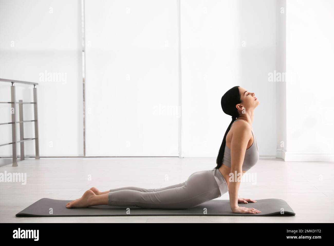 Young woman practicing cobra asana in yoga studio. Bhujangasana pose ...