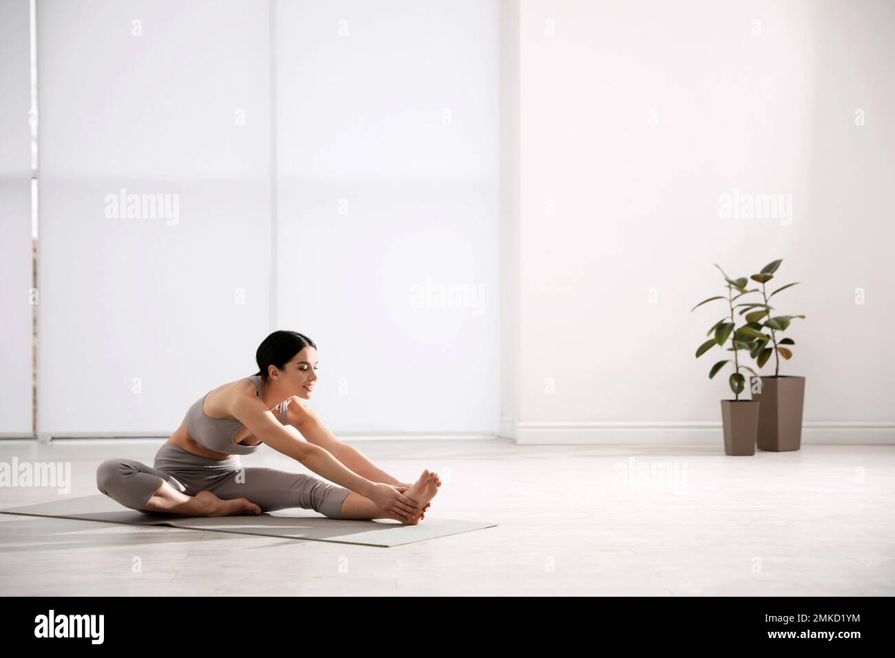 Young woman stretching leg in yoga studio. Janu Sirsasana pose variation Stock Photo