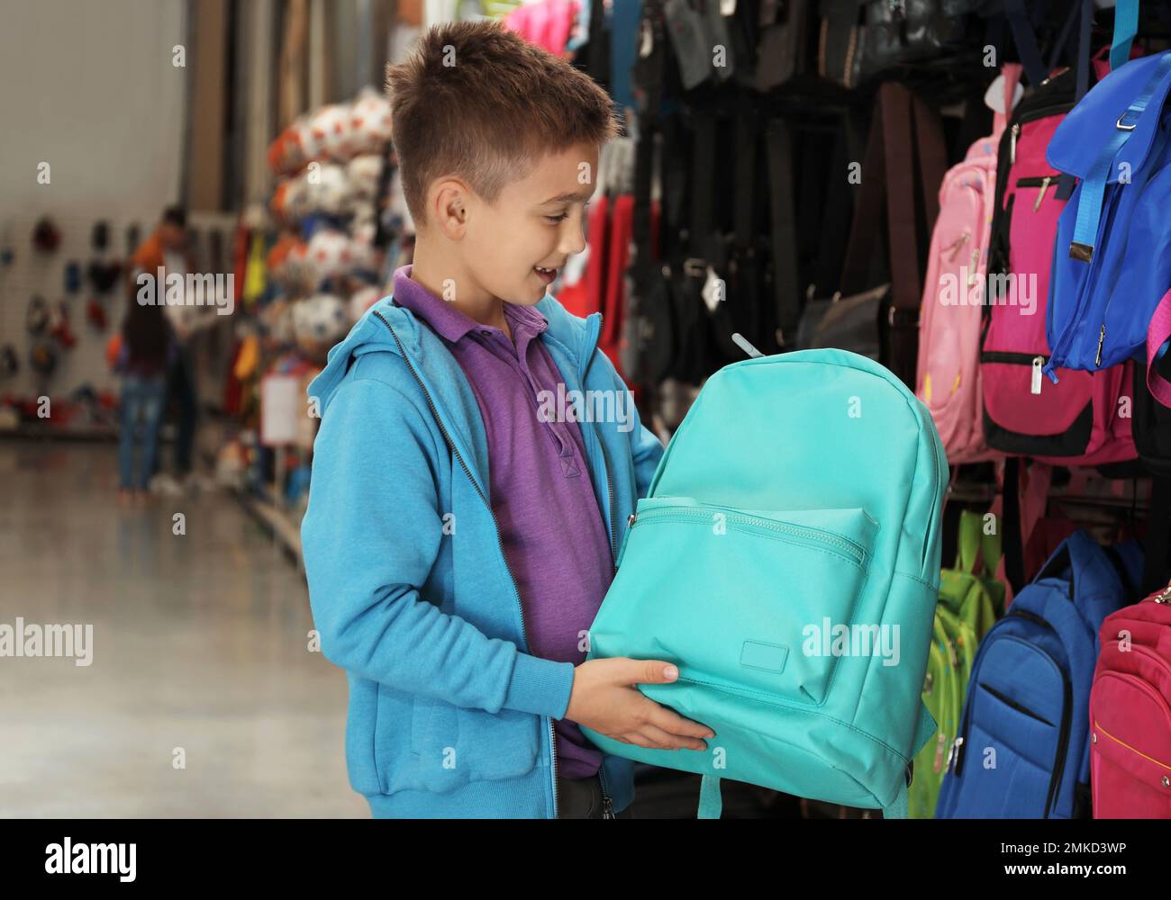 Little school boy choosing backpack in supermarket Stock Photo - Alamy