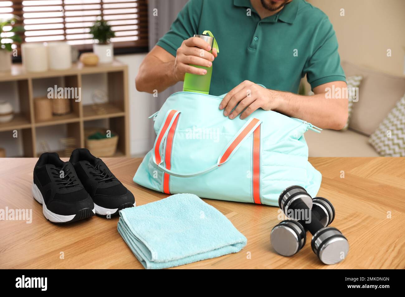 Man packing sports bag for training indoors, closeup Stock Photo