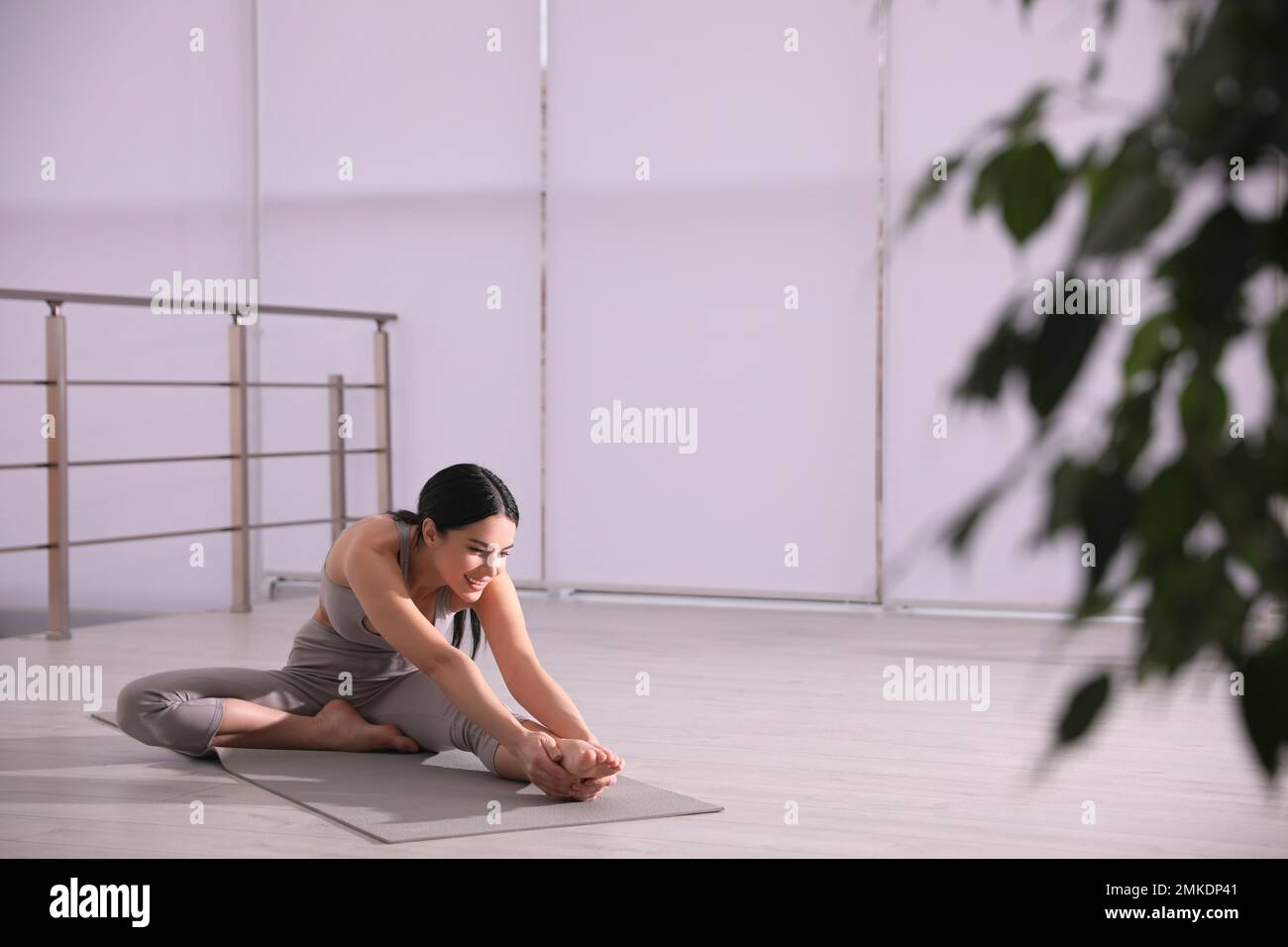 Young woman stretching leg in yoga studio. Janu Sirsasana pose variation Stock Photo