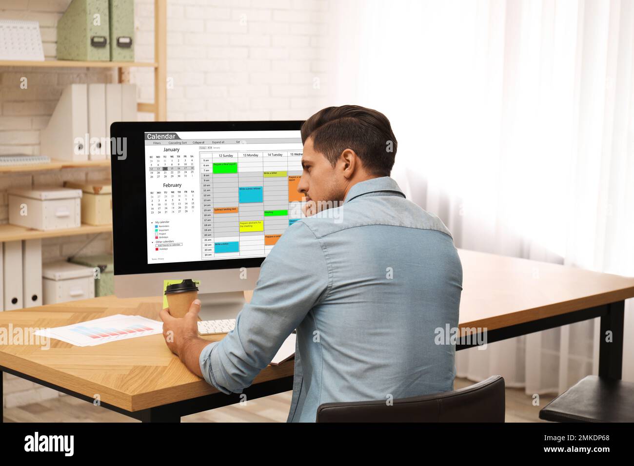 Handsome man using calendar app on computer in office Stock Photo - Alamy