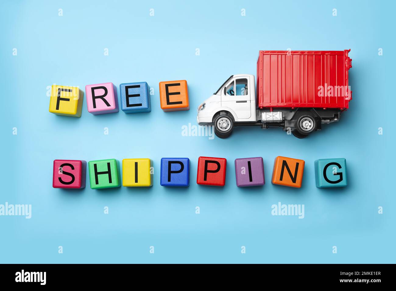 Toy truck with words FREE DELIVERY on blue background, flat lay. Logistics and wholesale concept Stock Photo