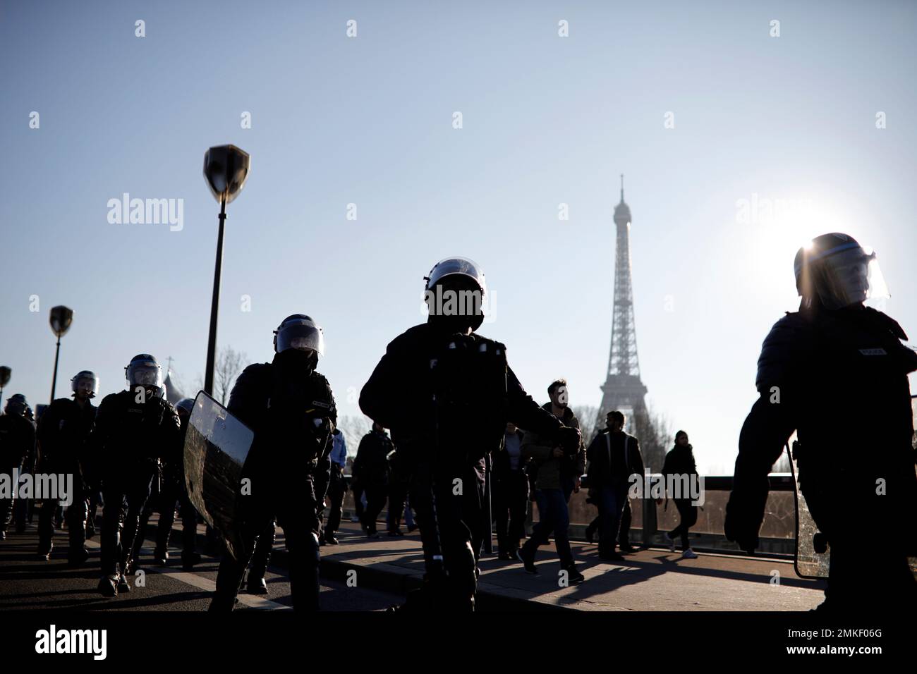 Yellow vest protesters flanked by police riot officers are silhouetted