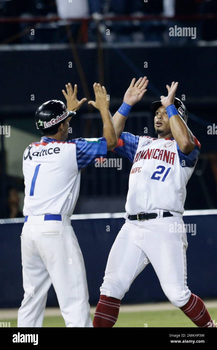 Moises Sierra, right, of the Dominican Republic's Estrellas Orientales high  fives with the batboy after scoring a run during the eight inning against  of Puerto Rico's, Cangrejeros de Santurce on their Caribbean