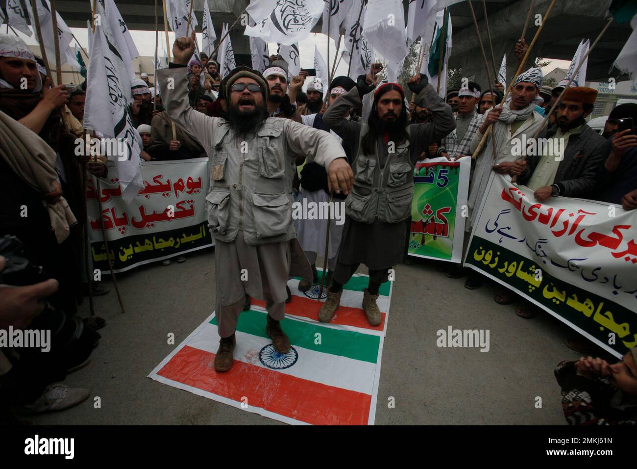 Pakistani protesters symbolically stand on an Indian flag and shout ...