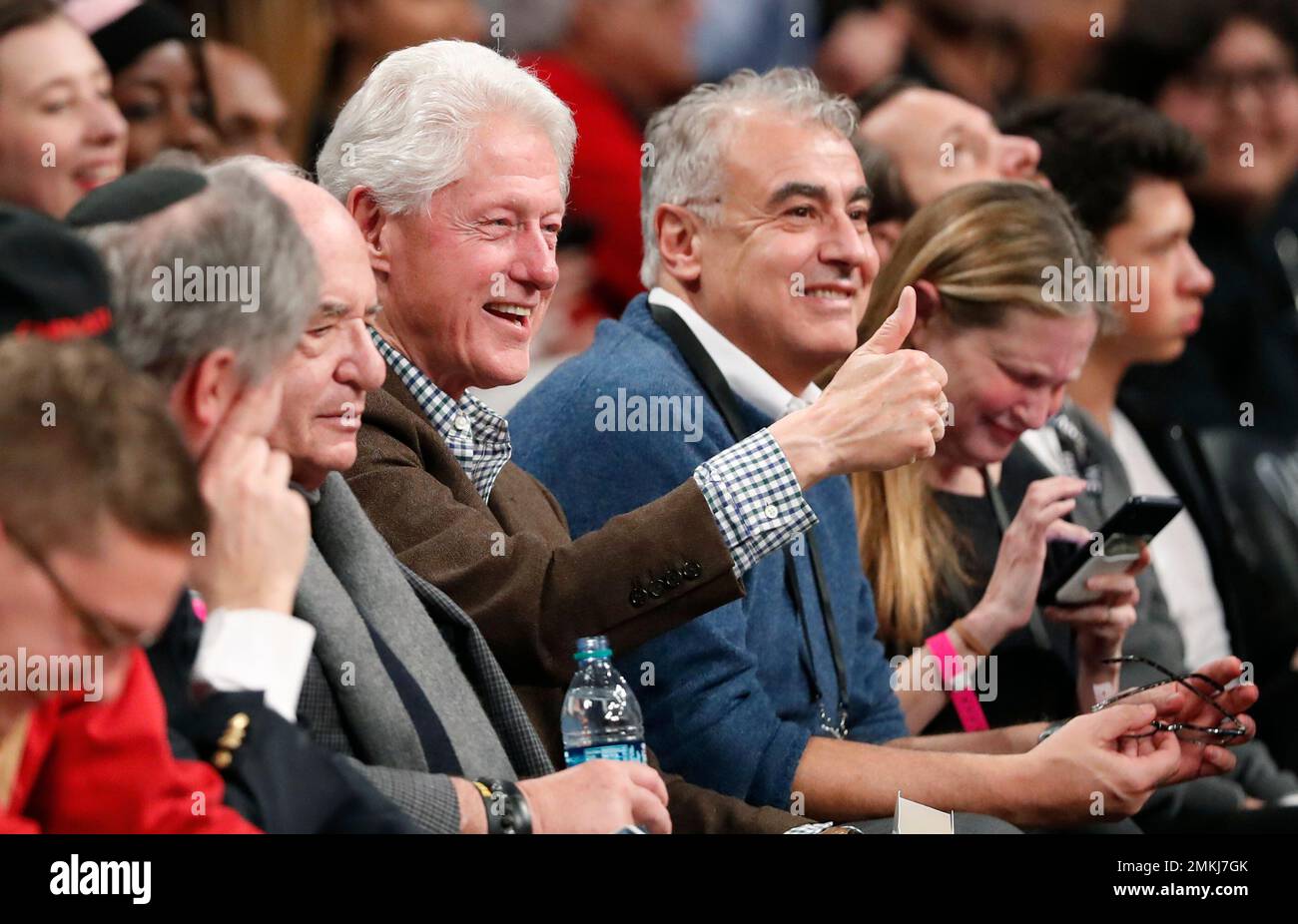 Milwaukee Bucks co-owner Marc Lasry (wearing blue sweater) laughs as former  President Bill Clinton, center, reacts to seeing his image on a giant video  screen above the court during a break in