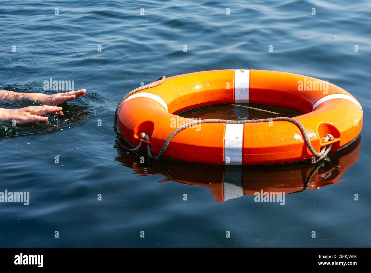 The man's hands reach for the lifebuoy in the water. The concept of