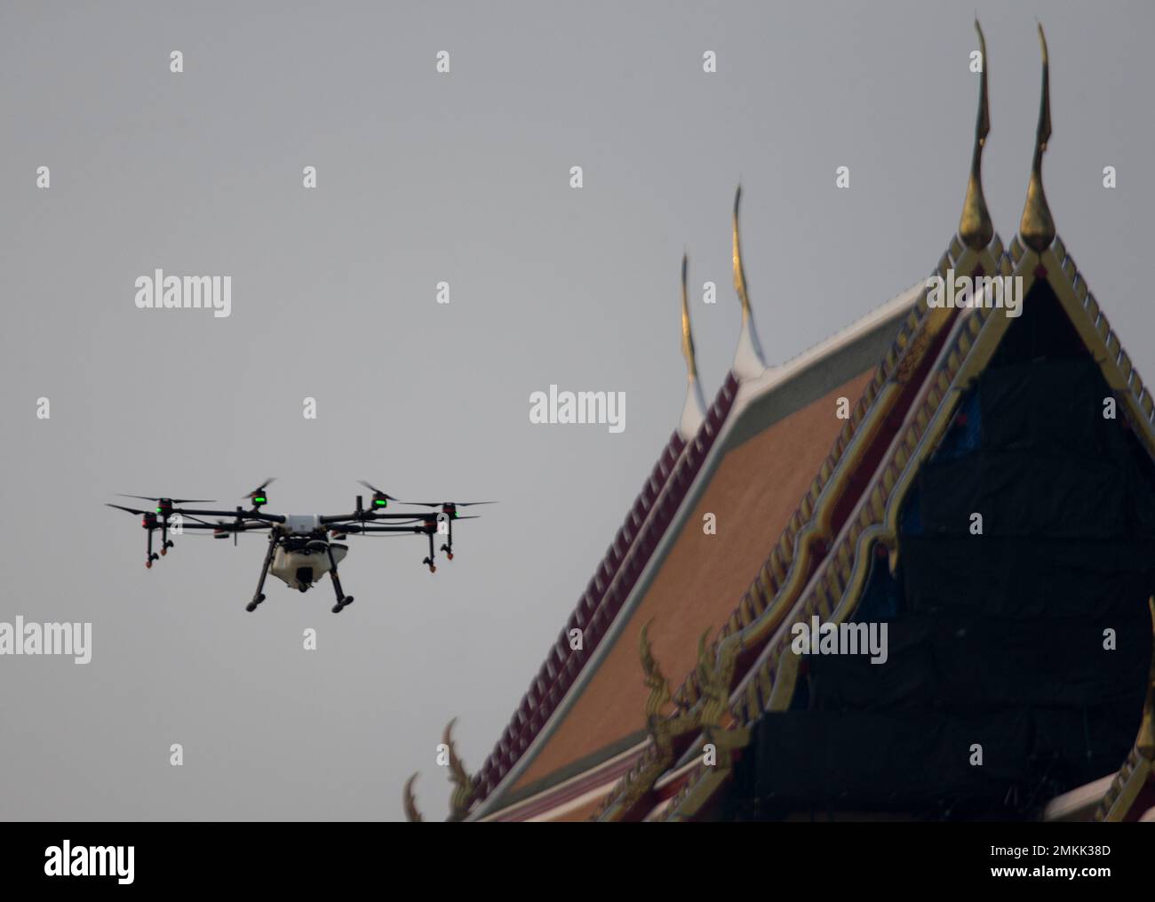 Drone pilots fly a waterspraying drone over the Suthat Temple in