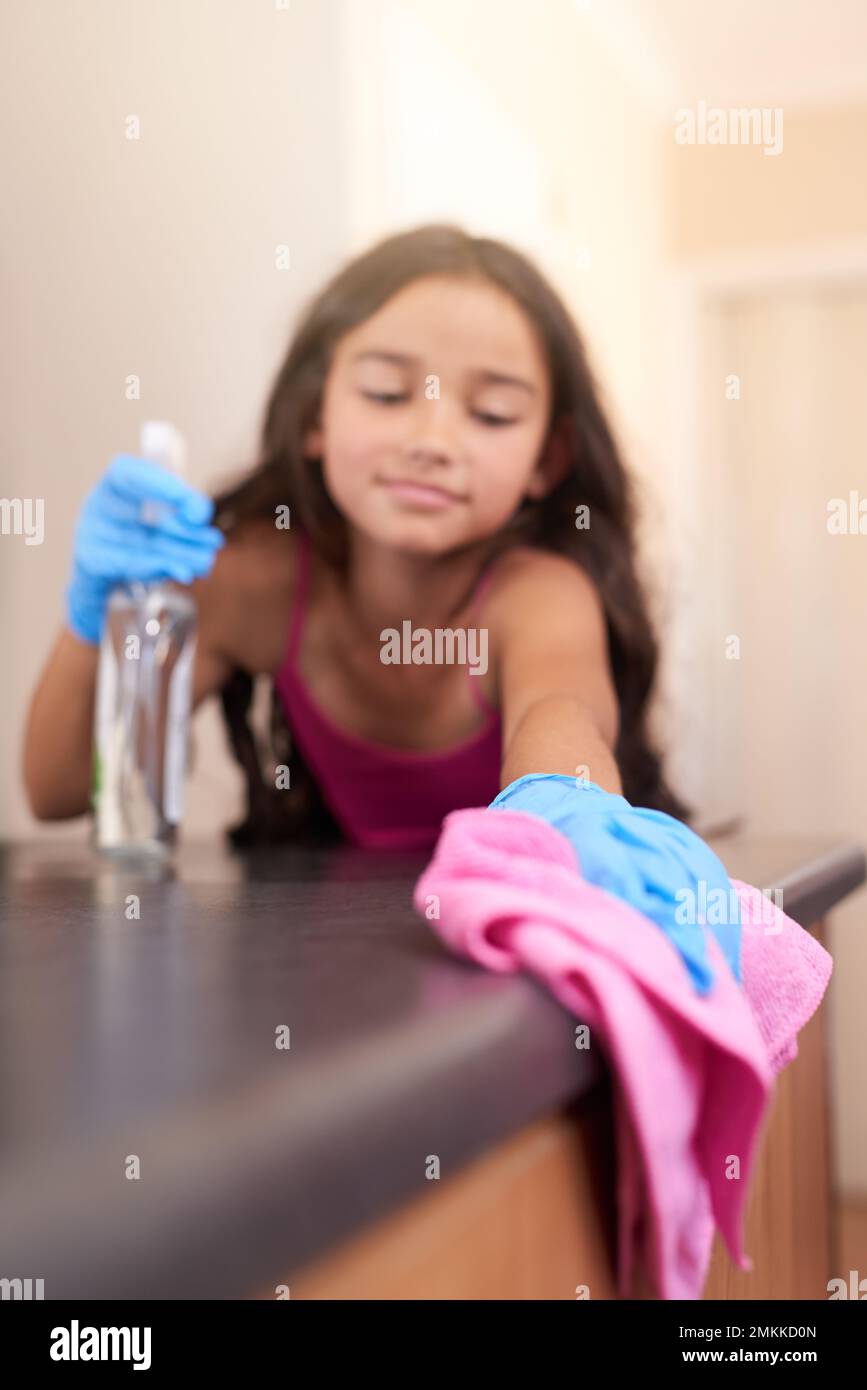 Cleaning up after herself. a young girl wiping a kitchen table with a