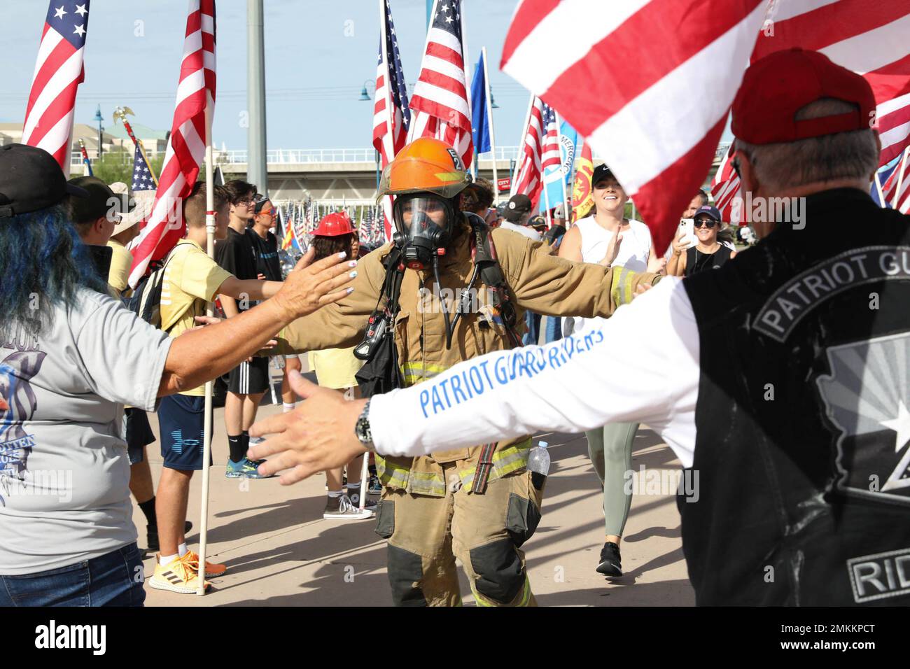 A volunteer runner wearing a fire fighting suit is embraced at the