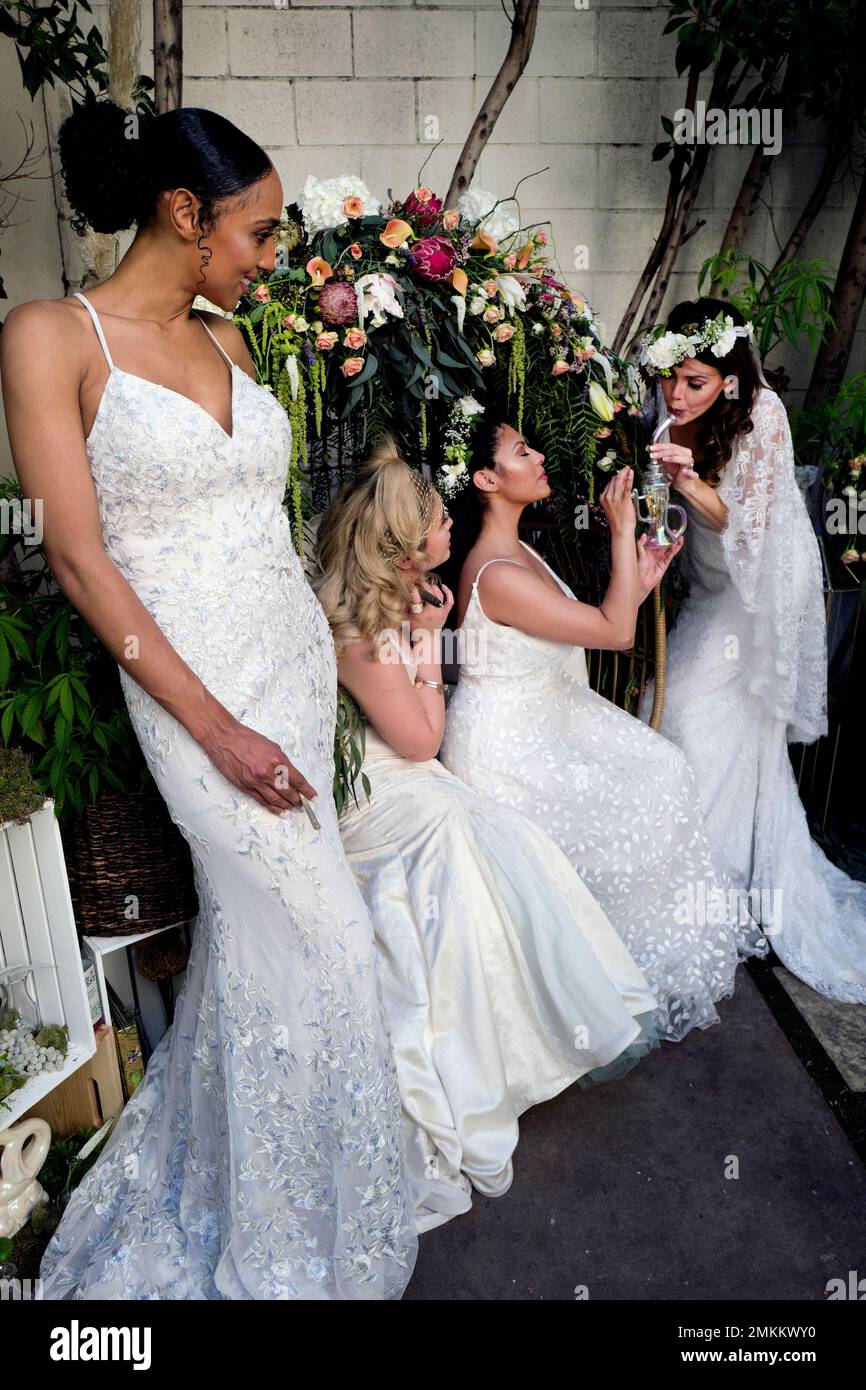 Models wearing wedding dresses designed by High Vibe Bride, Simply Bridal,  and Davids Bridal light up a water pipe during the Cannabis Wedding Expo in  Los Angeles on Saturday, Jan. 26, 2019. (