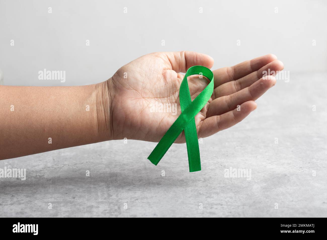 Hand holding a green ribbon. Cancer treatment concept Stock Photo Alamy