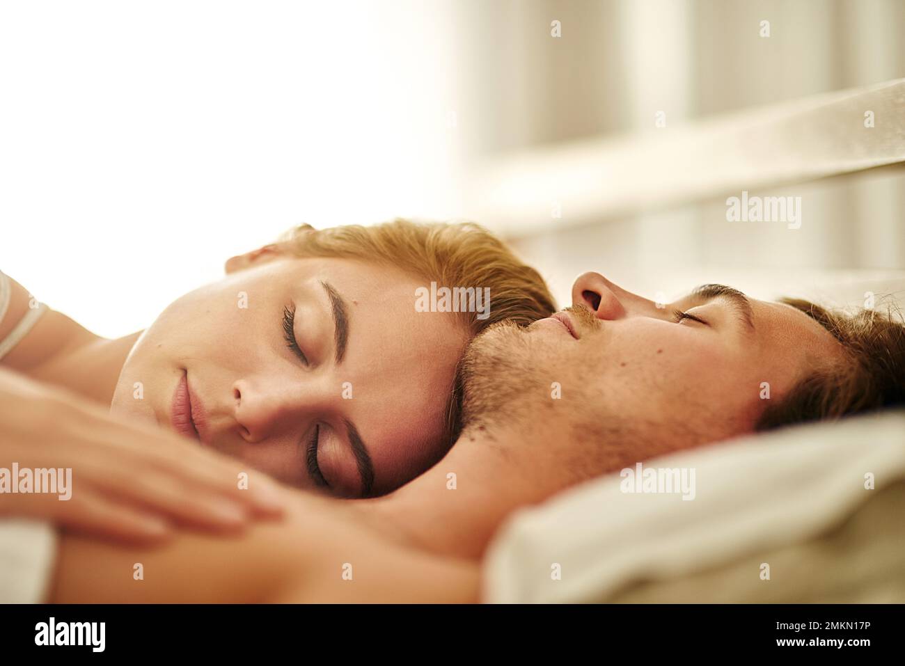 His heart beats for her. a young couple asleep in bed at home. Stock Photo