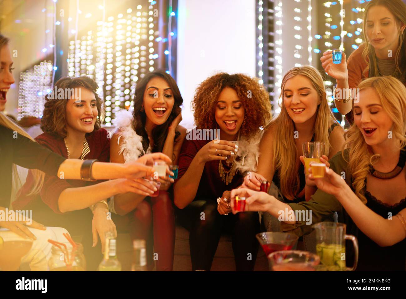 They know how to throw an awesome party. a group of young women drinking shots at a party. Stock Photo