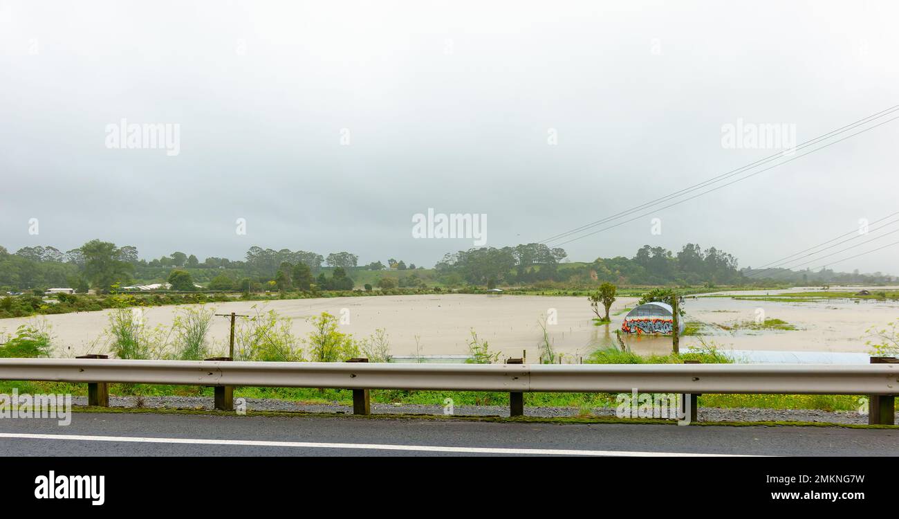 Tauranga New Zealand - January 28 2023; Flooded fields and half round corrugated iron shed off road in Bethlehem beside Wairoa River Stock Photo