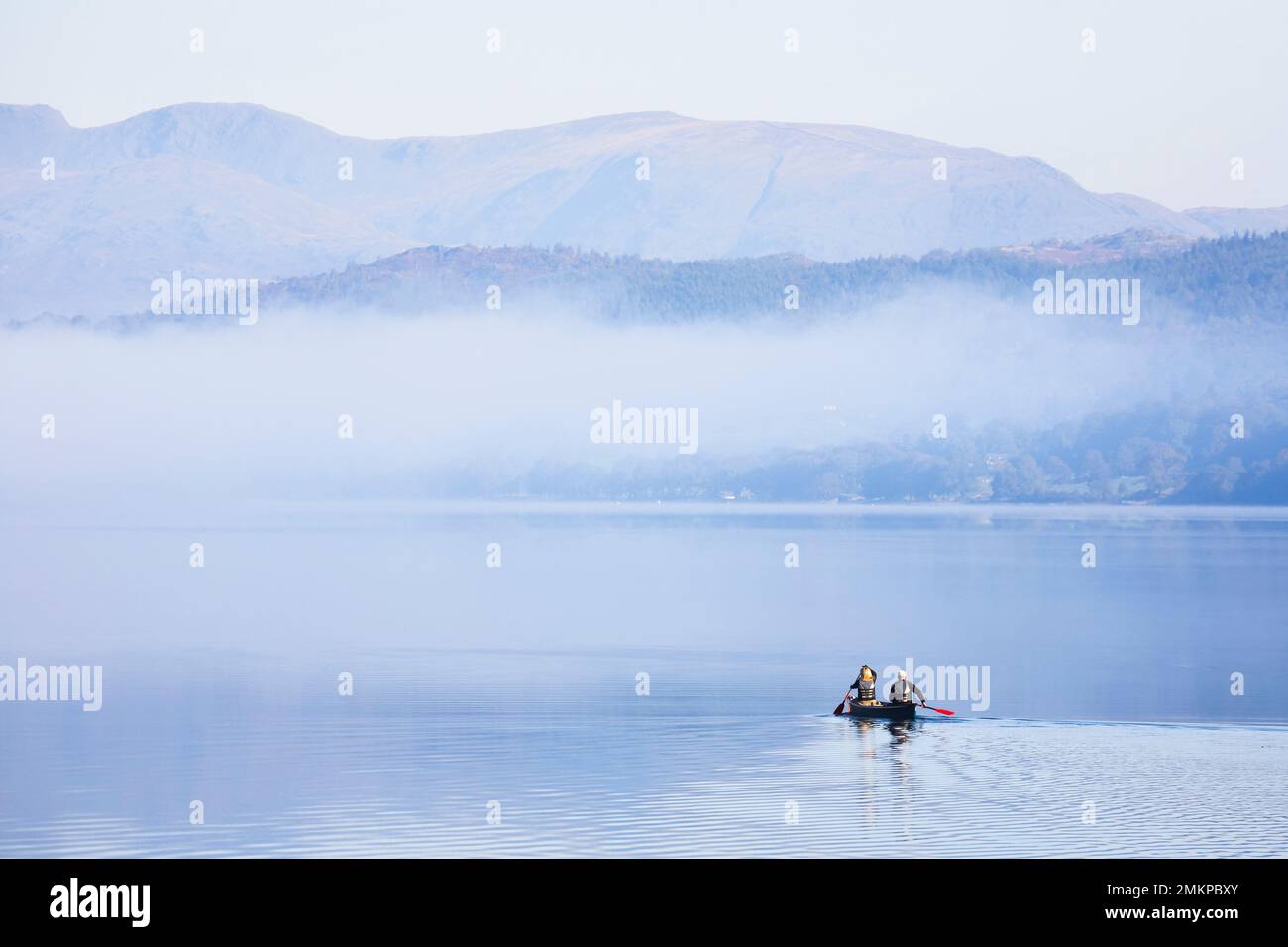 LAKE DISTRICT, UK - October 12, 2010. Couple paddling a double canoe on a lake, misty morning in autumn. Coniston Water, Lake District, England, UK Stock Photo
