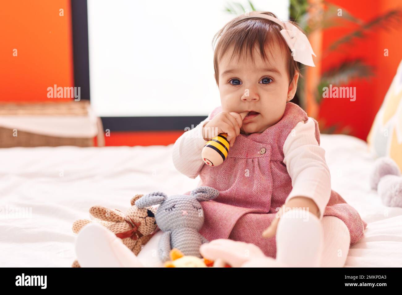 Adorable hispanic baby bitting maraca sitting on bed at bedroom Stock ...