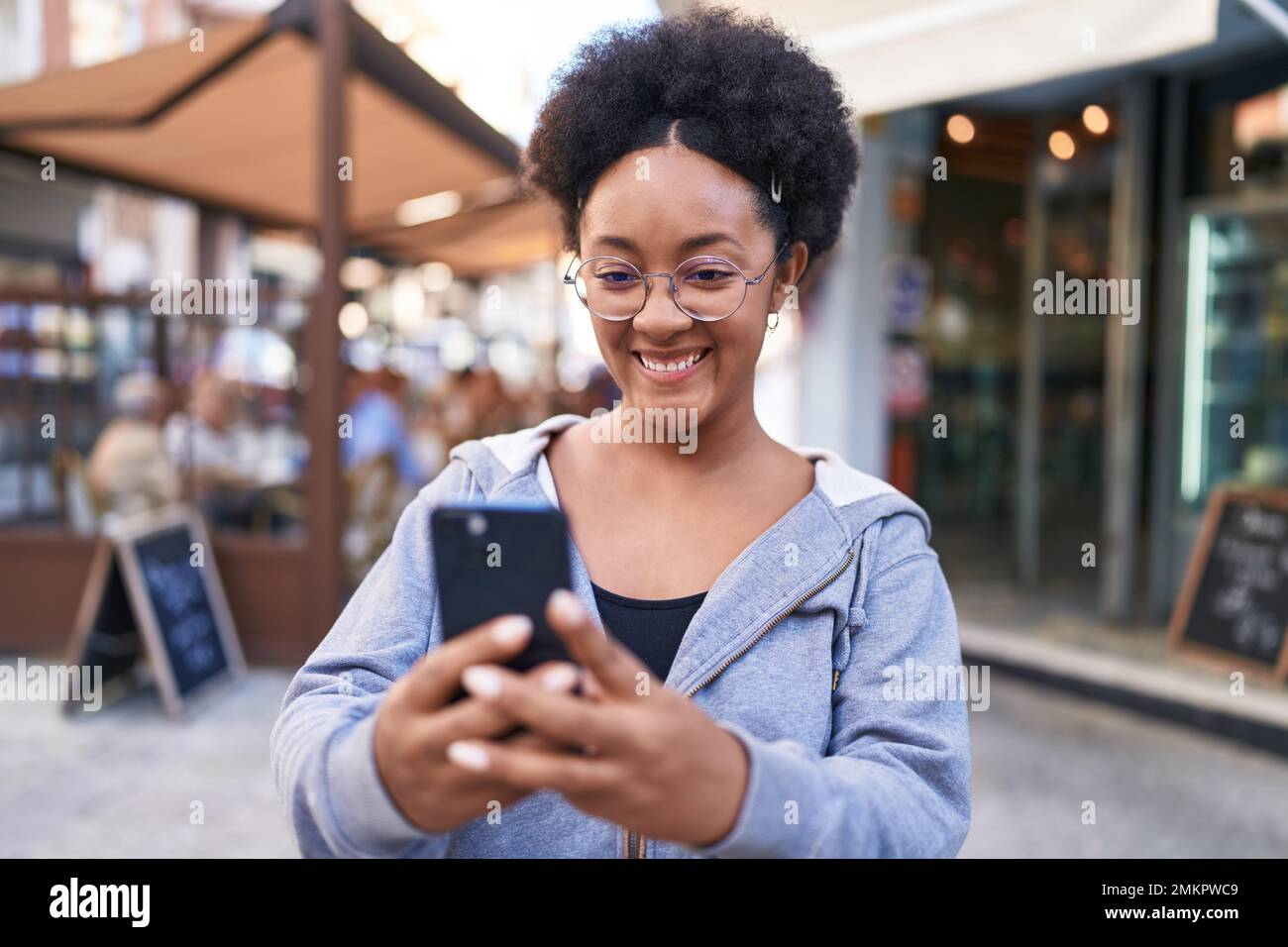 African american woman smiling confident using smartphone at coffee ...