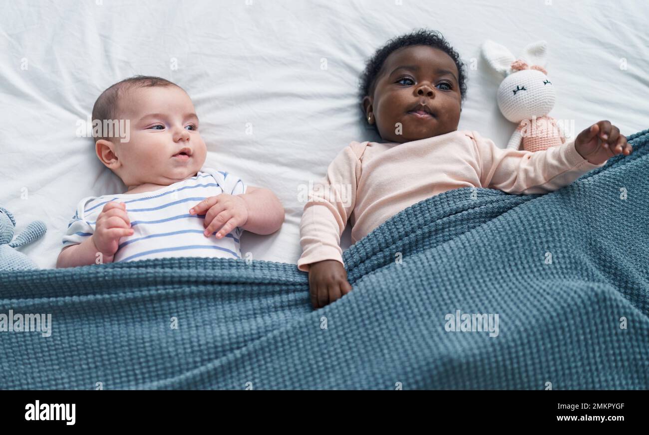 Two adorable babies lying on bed at bedroom Stock Photo - Alamy