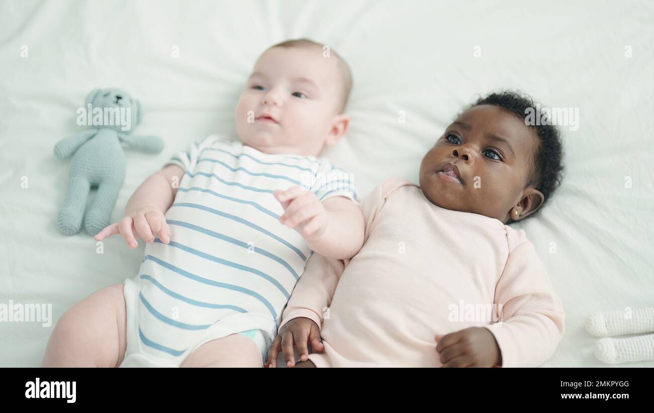 Two adorable babies lying on bed at bedroom Stock Photo - Alamy