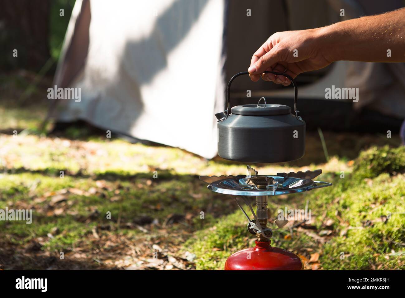 Cooking, heating a tourist kettle on a portable gas burner with a red