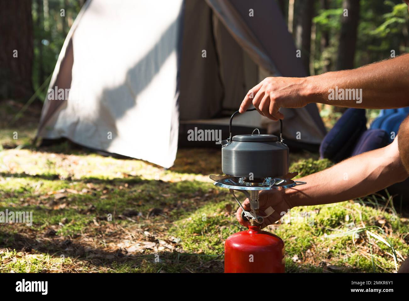 Cooking, heating a tourist kettle on a portable gas burner with a red